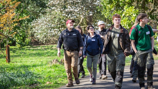 A group of apprentices gardeners on a guided walk at Winkworth Arboretum. They are walking along a pathway looking at trees.
